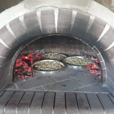 a brick oven with pizzas cooking in it at Къща за гости На Мечка in Oborishte