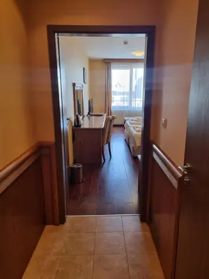 a hallway of a hotel room with a bed and a desk at Bellevue Residence RELAX ZONE in Bansko