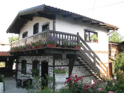a house with a balcony with potted plants on it at Oasis Guest House in Dobrinishte