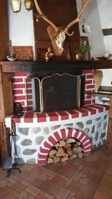 a red and white fireplace with a pile of wood at Oasis Guest House in Dobrinishte