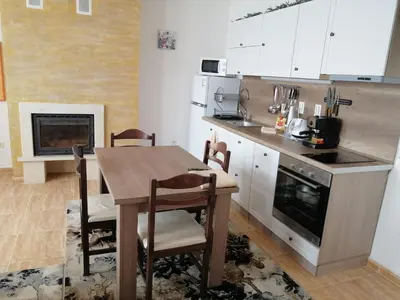 a kitchen with a wooden table and a fireplace at GRAND MONASTERY Apartment ``WHITE TALE`` in Pamporovo