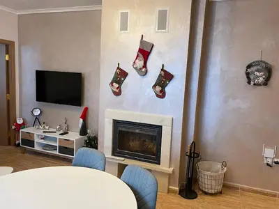 a living room with a fireplace with christmas ornaments on the wall at Гранд Манастира Частен Апартамент in Pamporovo