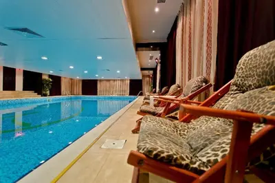a swimming pool in a hotel with chairs next to it at Гранд Манастира Частен Апартамент in Pamporovo