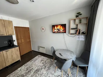 a living room with a table and chairs and a fireplace at MH Apartments in Bansko