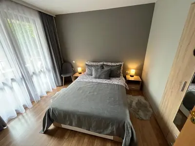a bedroom with a bed and two lamps on tables at MH Apartments in Bansko