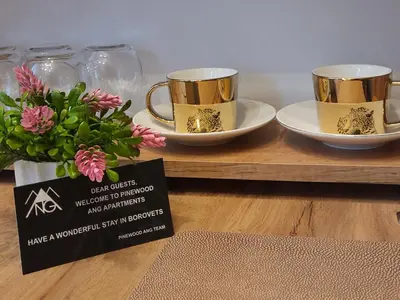 two gold cups and plates on a table with flowers at Pinewood ANG luxurious apartment A32 in Borovets