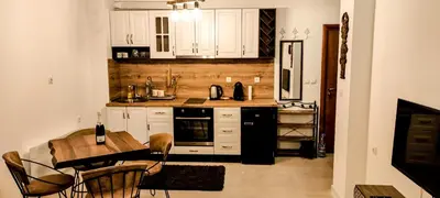 a kitchen with white cabinets and a table and chairs at Луксозен Апартамент Мечи Чал - Апартхотел Манастира 2 in Pamporovo