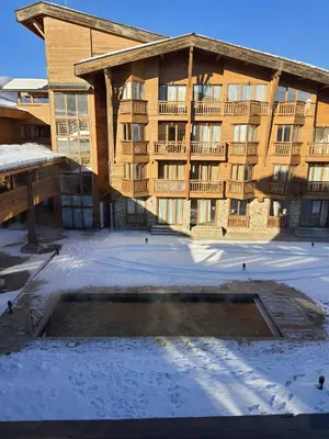 a large apartment building with a pool in the snow at Rustic Spa at Pirin Golf in Razlog
