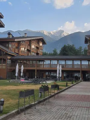 a large building with mountains in the background at Rustic Spa at Pirin Golf in Razlog