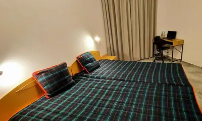a hotel room with a large bed with a plaid cover at BOGI SPA Apartment Pamporovo in Pamporovo