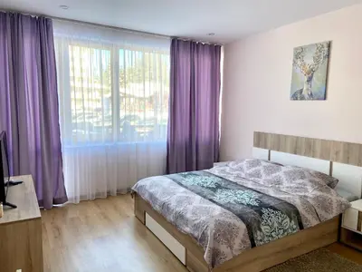 a bedroom with a bed and a window with purple curtains at Apartment in Studenets, Pamporovo in Pamporovo