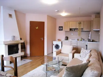 a living room with a couch and a table and a kitchen at Solar nest with fireplace and mountain view - near ski lift and center in Bansko