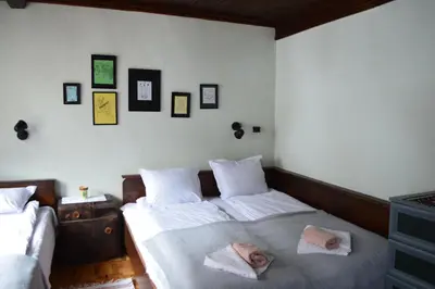 two beds in a bedroom with pictures on the wall at Yakusha - Якуша, къща за гости in Shiroka Lŭka