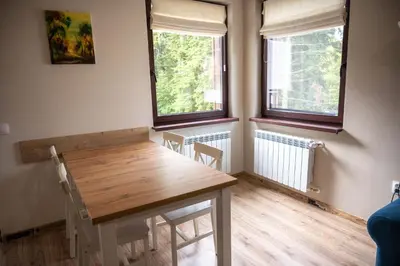 a dining room with a wooden table and two windows at All Seasons Apartments Borovets Gardens in Borovets