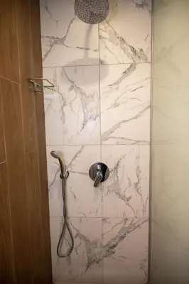 a shower stall with a white marble wall at All Seasons Apartments Borovets Gardens in Borovets
