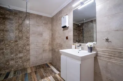 a bathroom with a white sink and a shower at Семеен хотел и ресторант Райски залив in Golyama Zhelyazna