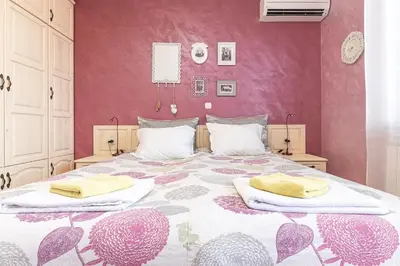 a bedroom with a large bed with a pink wall at Семеен хотел и ресторант Райски залив in Golyama Zhelyazna