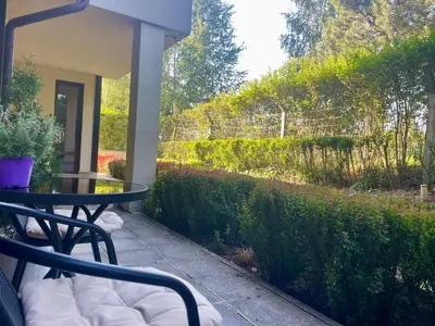 a patio with a table and a hedge at Ground floor 2-bedrooms, 2-bathrooms apartment near Bansko in a complex with pools and SPA included in Razlog