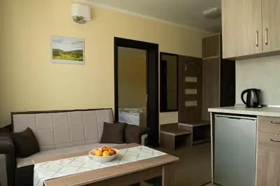 a kitchen and a living room with a bowl of fruit on a table at Hotel Niken in Pamporovo