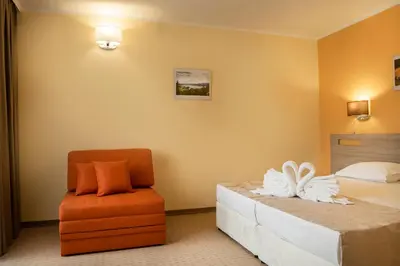 a bedroom with a bed and a chair at Hotel Niken in Pamporovo