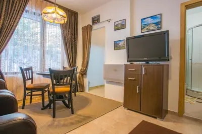 a living room with a television and a table and chairs at Cozy One-Bedroom apartment with Nature View by Flat Mаnager in Razlog