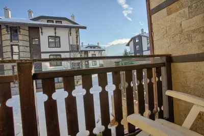 a balcony with a bench and buildings in the background at Cozy One-Bedroom apartment with Nature View by Flat Mаnager in Razlog
