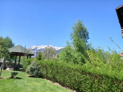 a garden with a hedge and a gazebo and mountains at Студио Snow day в Green life в Банско in Bansko