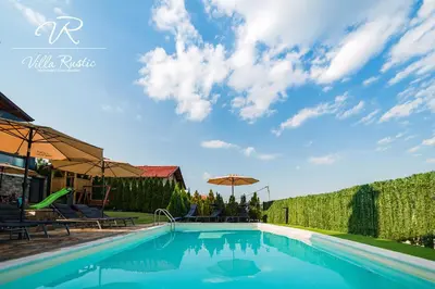 a swimming pool with chairs and umbrellas at Вила Рустик / Villa Rustic in Kyustendil