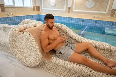 a man in a swimsuit laying on a couch in a swimming pool at Camping Alliance in Plovdiv