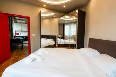a bedroom with a large white bed and a mirror at Elegant 2bdr Apartment with a Balcony in Sofia
