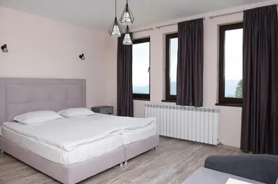 a bedroom with a large white bed and windows at Вила Релакс in Pamporovo