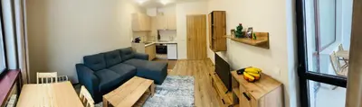 a living room with a blue couch and a kitchen at Cactus Apartment in Borovets