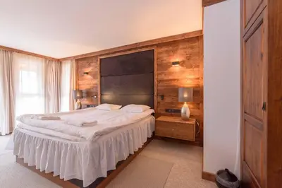 a bedroom with a large bed with a wooden wall at Finest Luxury Penthouse Bansko Royal Towers in Bansko