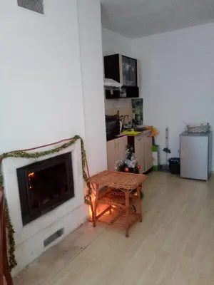 a living room with a fireplace and a chair at Синьо небе in Bansko