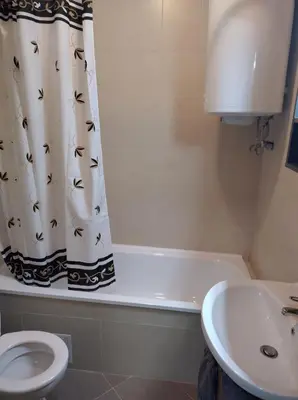 a bathroom with a shower curtain with a toilet and a sink at St John Park Boutique room Gero in Bansko