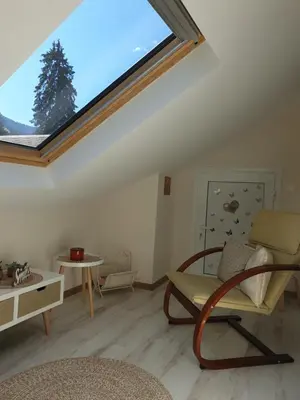 a living room with a skylight and a chair at Borovets Cozy Mountain Apartments in Borovets