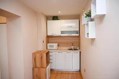 a small kitchen with white cabinets and a microwave at The White Horse Apartments in Borovets