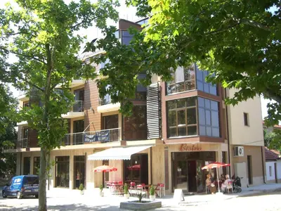 a building with tables and umbrellas in front of it at Apartament Fantasy Hisarya in Hisarya