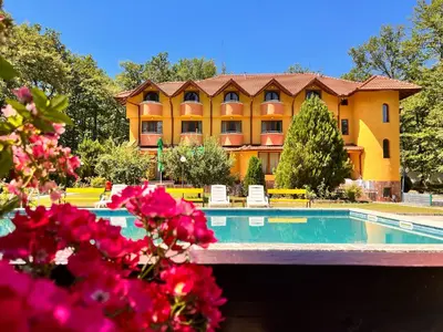 a resort with a swimming pool and pink flowers at Почивна база 