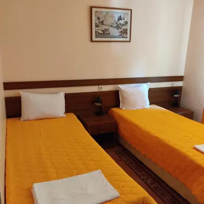 two beds in a hotel room with yellow sheets at Почивна база 