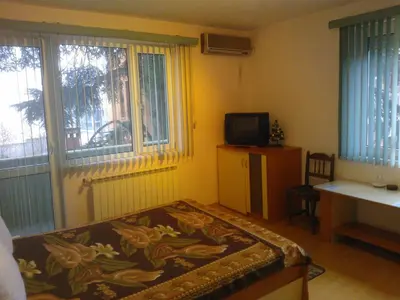 a room with a bed and a tv and windows at Hotel Tsarevets in Asenovgrad