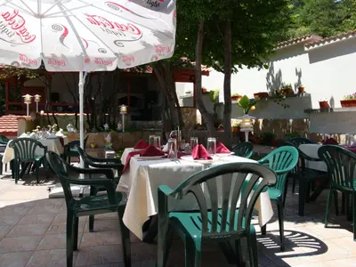 an outdoor table with chairs and an umbrella at Family Hotel Diana in Lyaskovo
