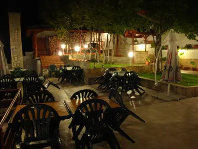 a group of tables and chairs at a restaurant at night at Family Hotel Diana in Lyaskovo
