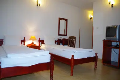 two beds in a room with a tv and a room with at Family Hotel Diana in Lyaskovo