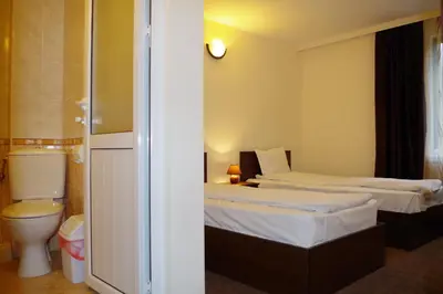 a hotel room with two beds and a toilet at Family Hotel Diana in Lyaskovo
