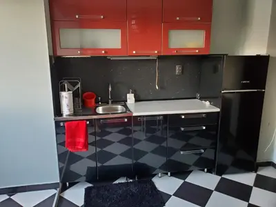 a small kitchen with red cabinets and a black and white floor at Романтично Място Ани in Plovdiv