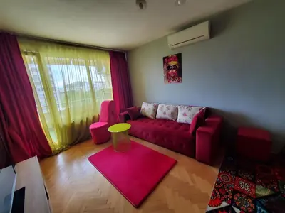 a living room with a red couch and a pink rug at Романтично Място Ани in Plovdiv