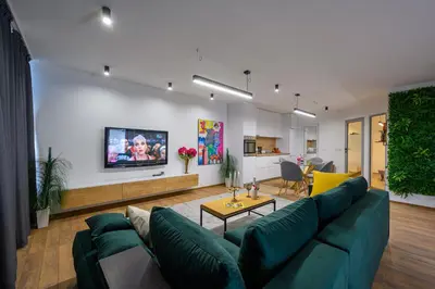 a living room with a green couch and a tv at Гардън Апарт in Blagoevgrad