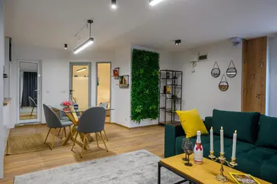 a living room with a green couch and a table at Гардън Апарт in Blagoevgrad