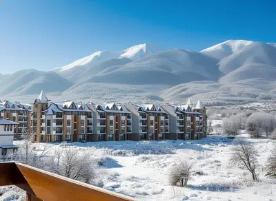 a building in the snow with mountains in the background at Belvedere Holiday Club К501 in Bansko